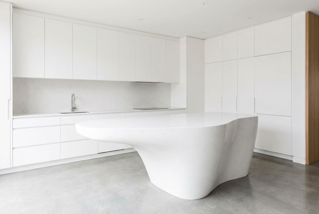 Minimalist cuisine with handleless white cabinets, stone countertop, and single brass pendant